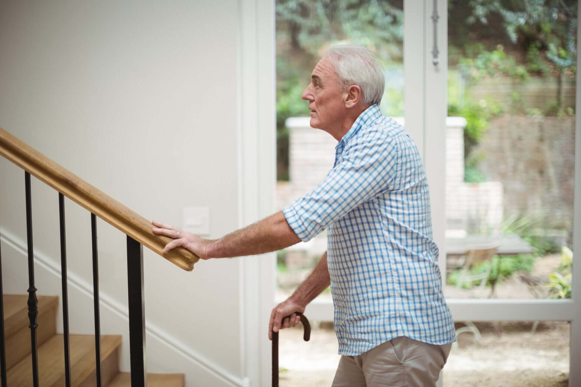 Elderly man standing at the bottom of indoor stairs