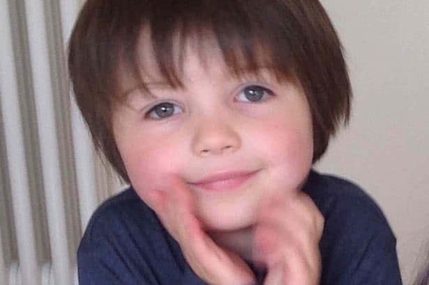 Smiling child with brown hair and blue eyes.