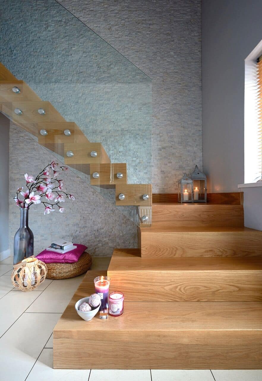 Modern wooden staircase with a decorative vase and candles.