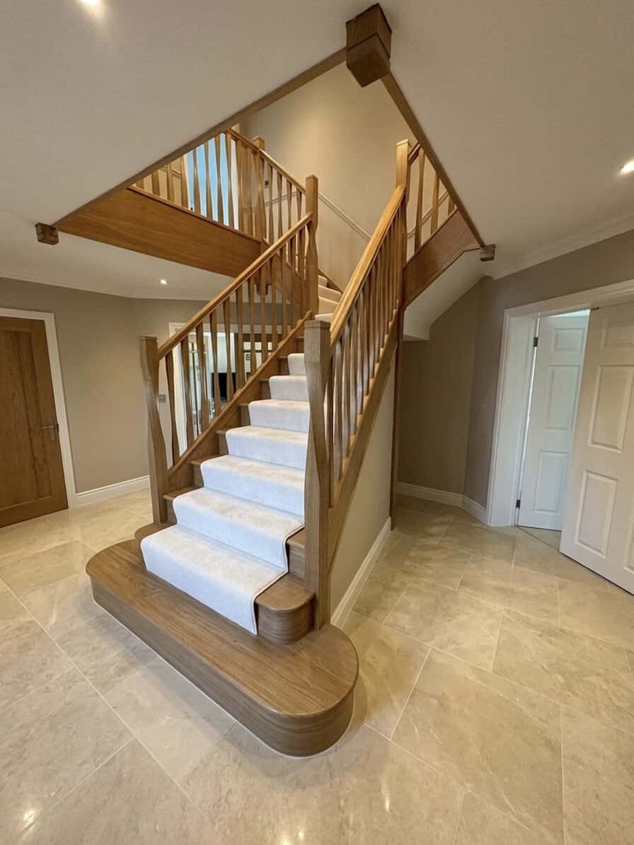 T-shaped oak staircase with twisted wooden spindles and posts, a cream carpet runner and broad rounded feature steps beneath a matching gallery landing.