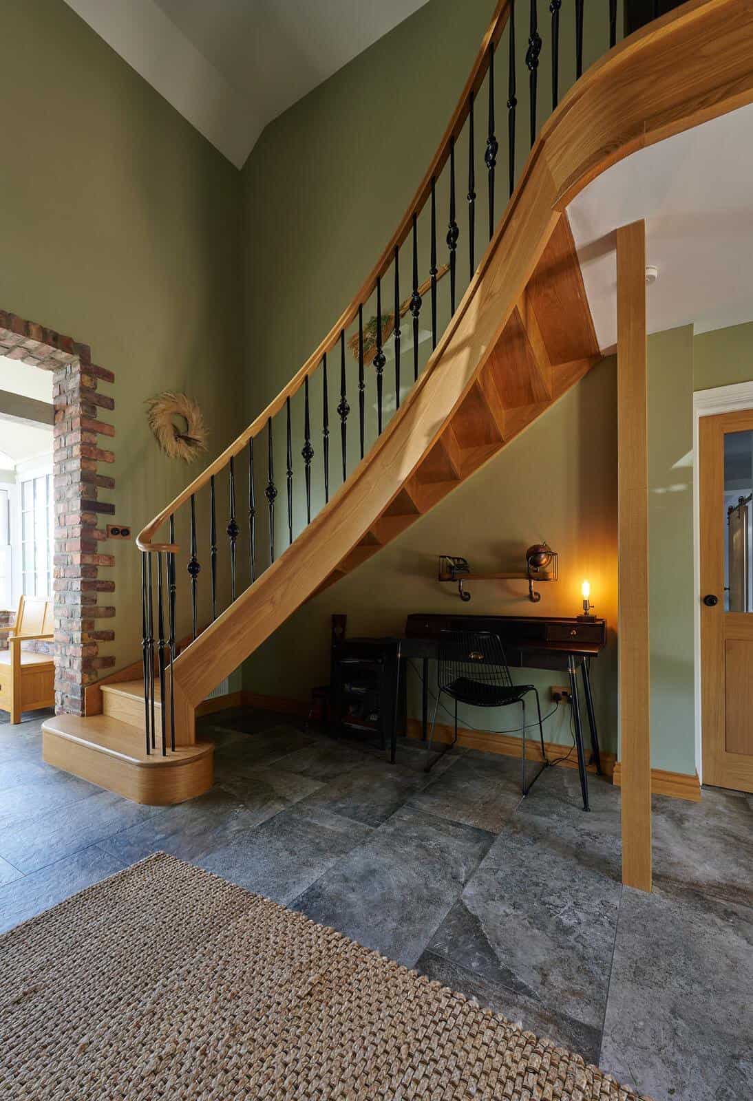 A flared helical staircase featuring a solid oak wreath handrail and solid steel spindles with a durable powder-coated finish