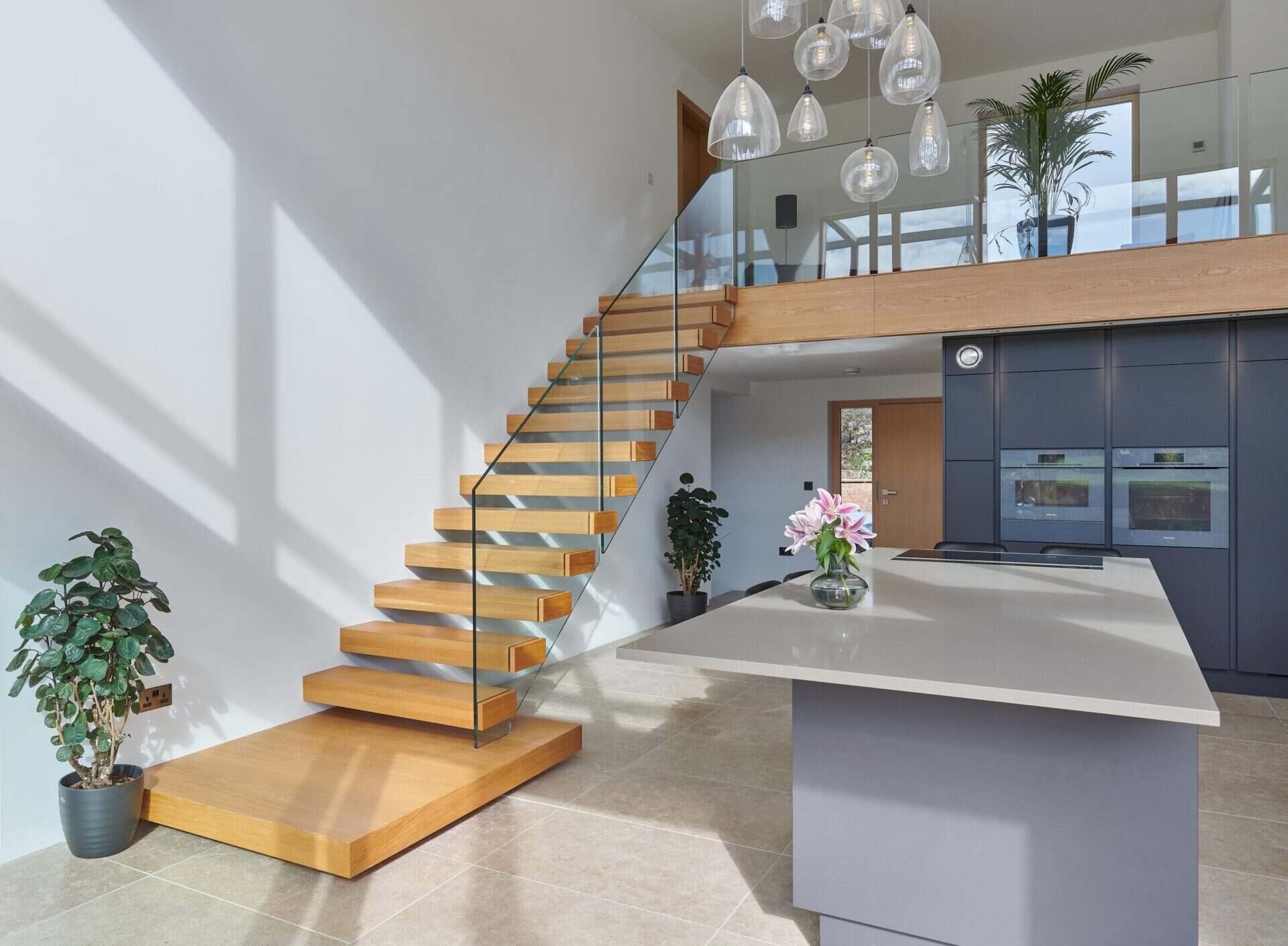 Image of floating staircase leading into a kitchen with kitchen island