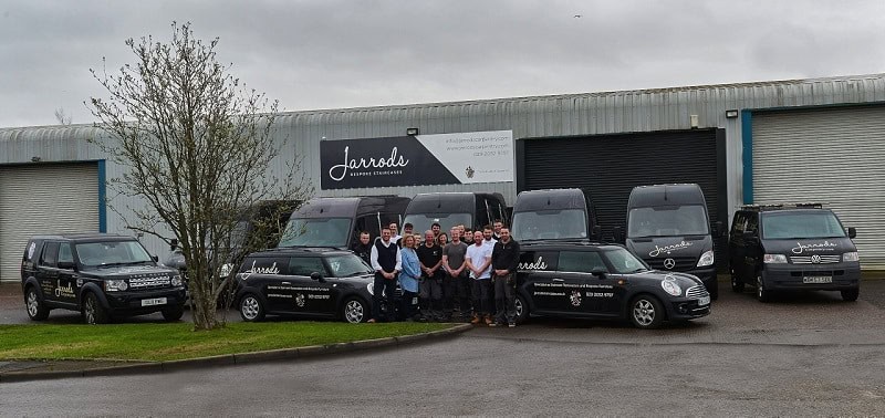 A group of people stands in front of vehicles.