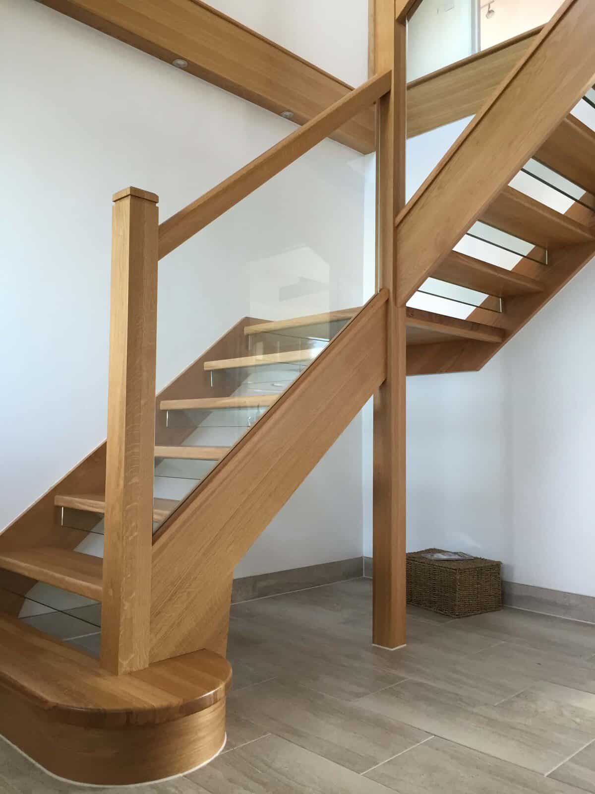 Oak open-riser staircase with glass balustrades, square newel posts and a rounded wooden feature step.