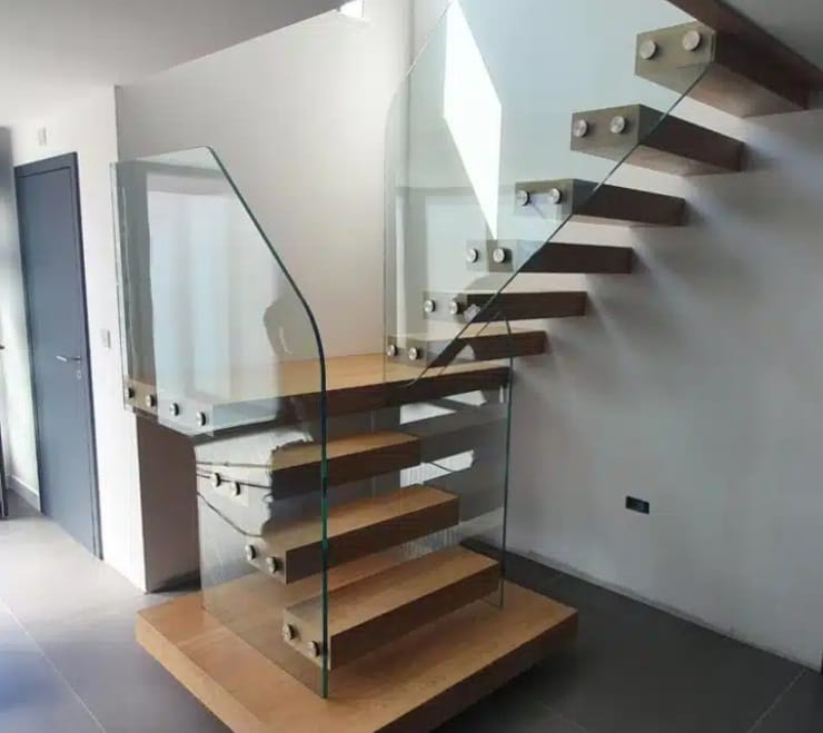 Floating wooden staircase with open treads and frameless glass panels attached with round metal fixings.