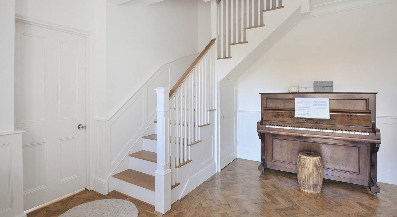 This staircase combines oak and white finishes, featuring a cut-string design, white square spindles, white box newel posts and a solid oak handrail