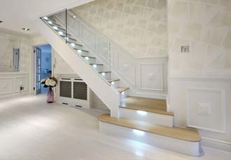 Modern staircase with glass railing and light.