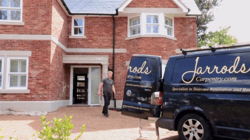 Worker leaving a home with a branded van parked.