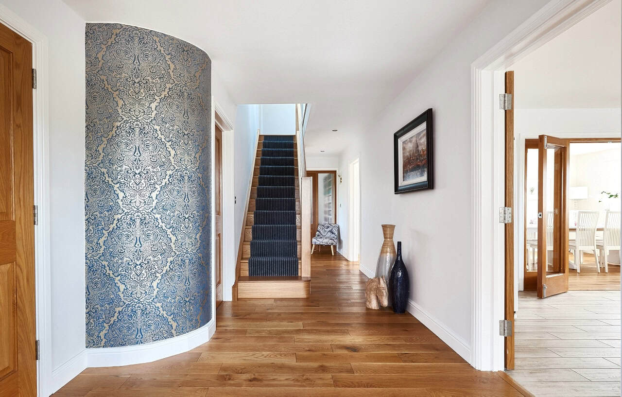 Modern hallway with wallpaper, stairs, and vases.