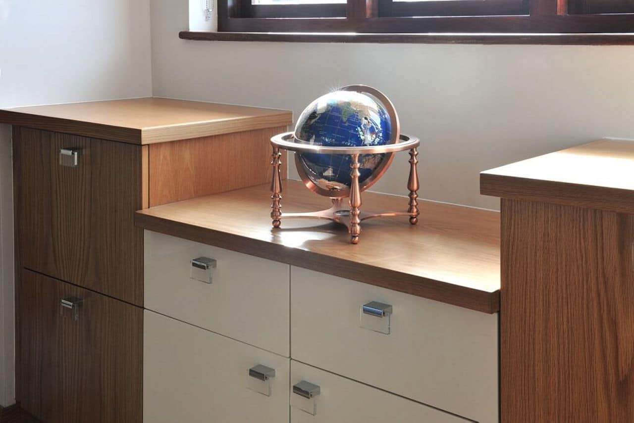 Fitted study cabinets with wood-grain cupboards, cream drawer fronts and a recessed wooden surface beneath a window.