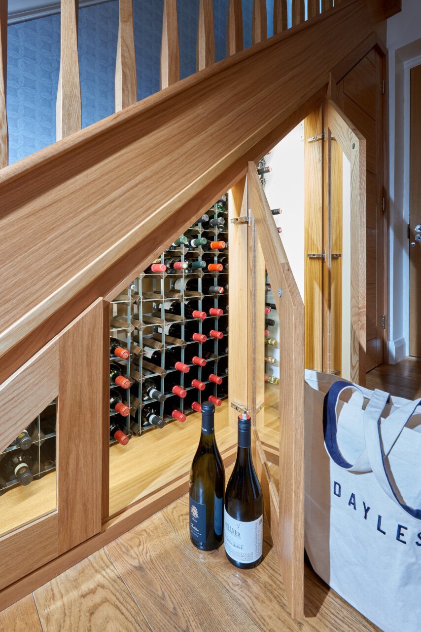 Wine storage beneath a staircase with two bottles.