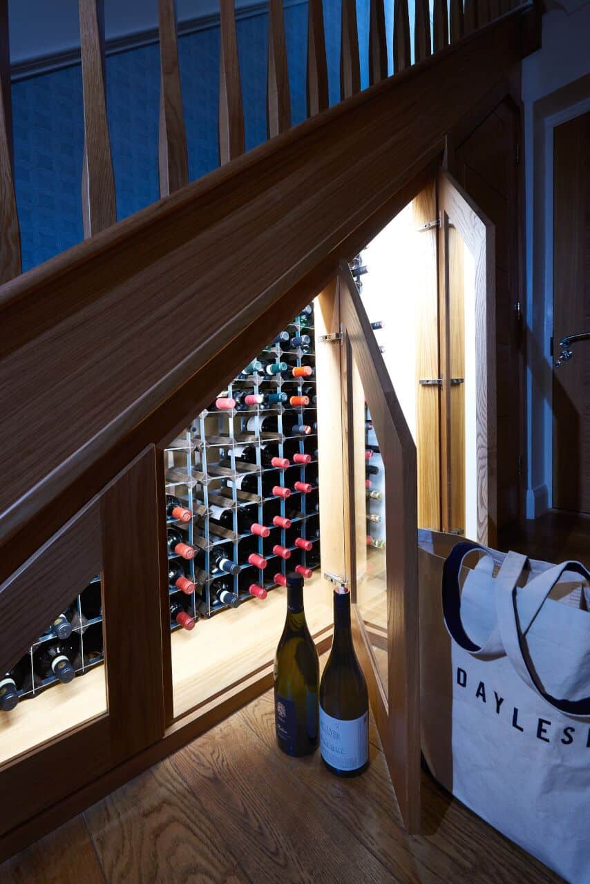 Wine rack under stairs with two bottles displayed.