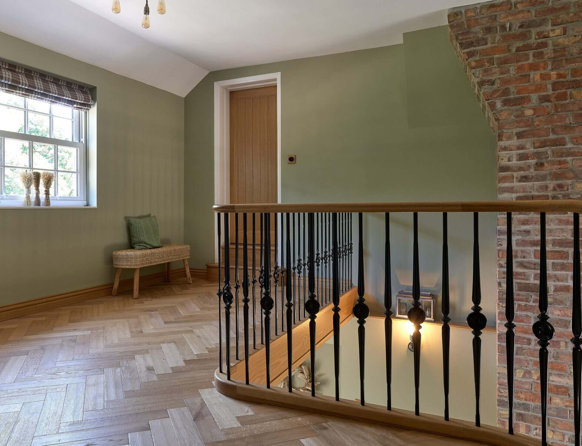 Elegant wooden staircase with black balustrades and brick wall detail.